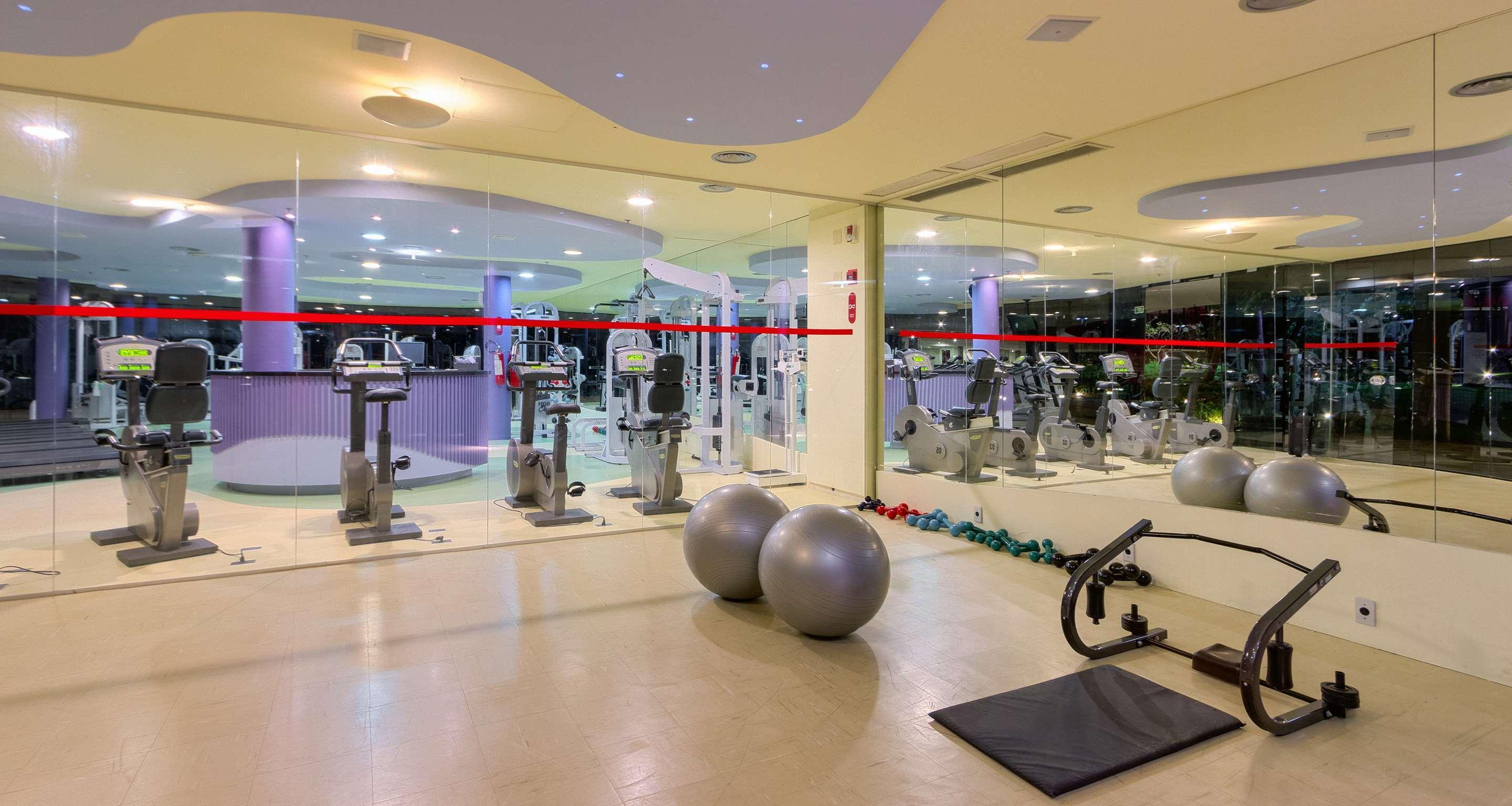 Royal Tulip Brasilia Alvorada Hotel Exterior foto The photo depicts a gym or fitness area. In the foreground, there are two large exercise balls and a mat on the floor. Behind them, there is a wall of mirrors that reflects various gym equipment, including exercise machines and bikes. The lighting in